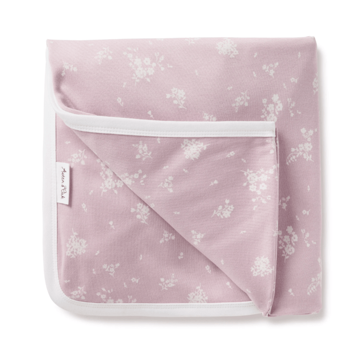 An Aster & Oak Organic Cotton Baby Swaddle Wrap with a hand-illustrated print of pink blanket with white flowers on it.