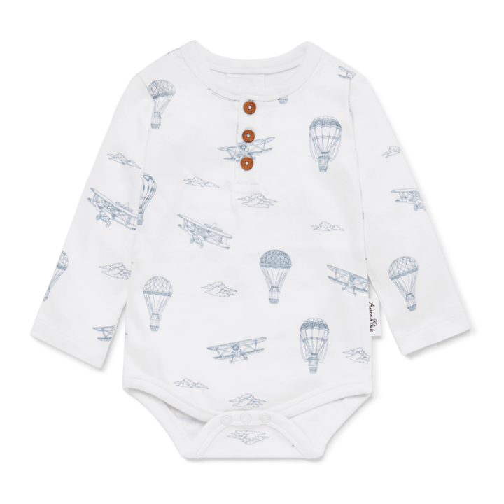 Introducing the Aster & Oak Organic Henley Long-Sleeved Onesie in the FOX WOODS design, a wonderful addition to your baby's wardrobe. This charming onesie is crafted from soft organic cotton, featuring blue sketches of vintage airplanes and hot air balloons. It is designed with three brown buttons on the front for added charm, making it perfect for your little one.