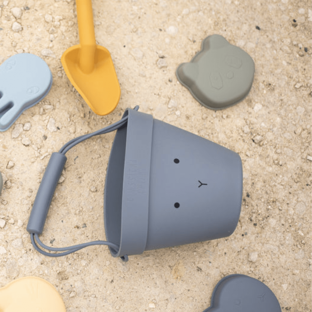 A group of Classical Child eco-friendly beach toys and a bucket laying on the ground.