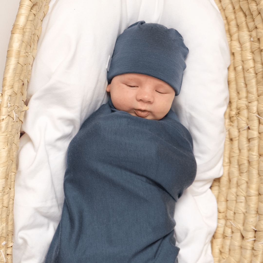 Baby-Swaddled-in-Babu-Merino-Swaddle-Wrap-Babu-Denim-In-Bassinet-Naked-Baby-Eco-Boutique