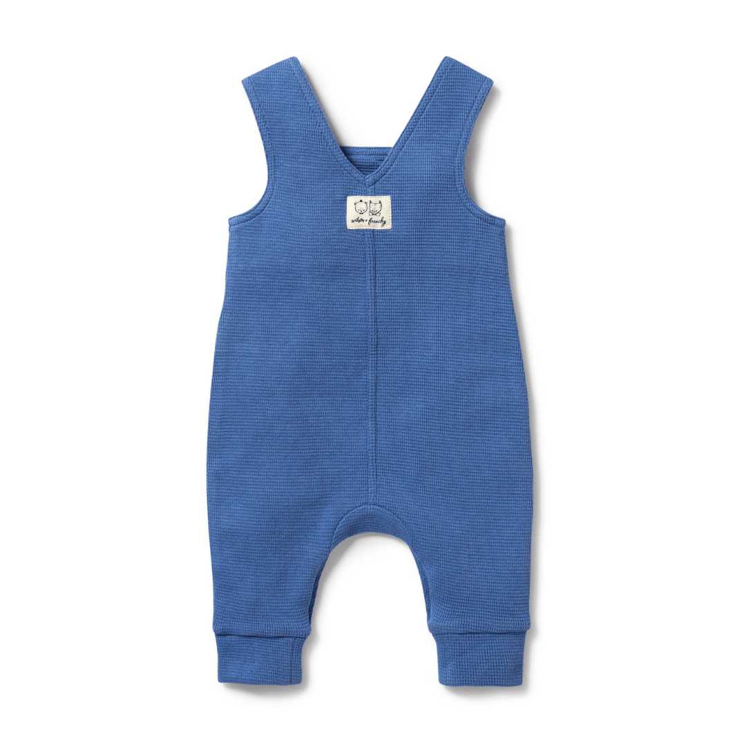 The Wilson & Frenchy Organic Waffle Overalls in 'Brilliant Blue' are crafted from GOTS-certified organic cotton for ultimate comfort and sustainability. These overalls feature thick straps and a small white label on the chest, perfect for babies aged 18-24 months.