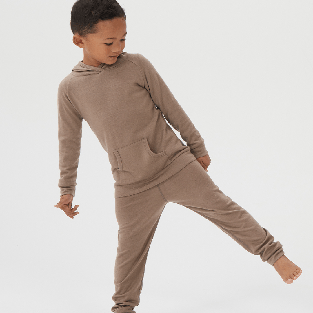 Boy-Standing-on-One-Leg-Wearing-Babu-Merino-Cuffed-Pants-Walnut-Naked-Baby-Eco-Boutique