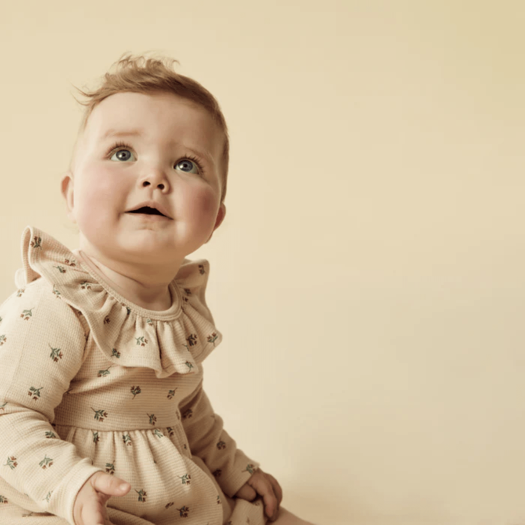 Close-Up-Of-Little-One-Wearing-Wilson-And-Frenchy-Organic-Waffle-Long-Sleeved-Ruffle-Dress-Emily-Floral-Naked-Baby-Eco-Boutique