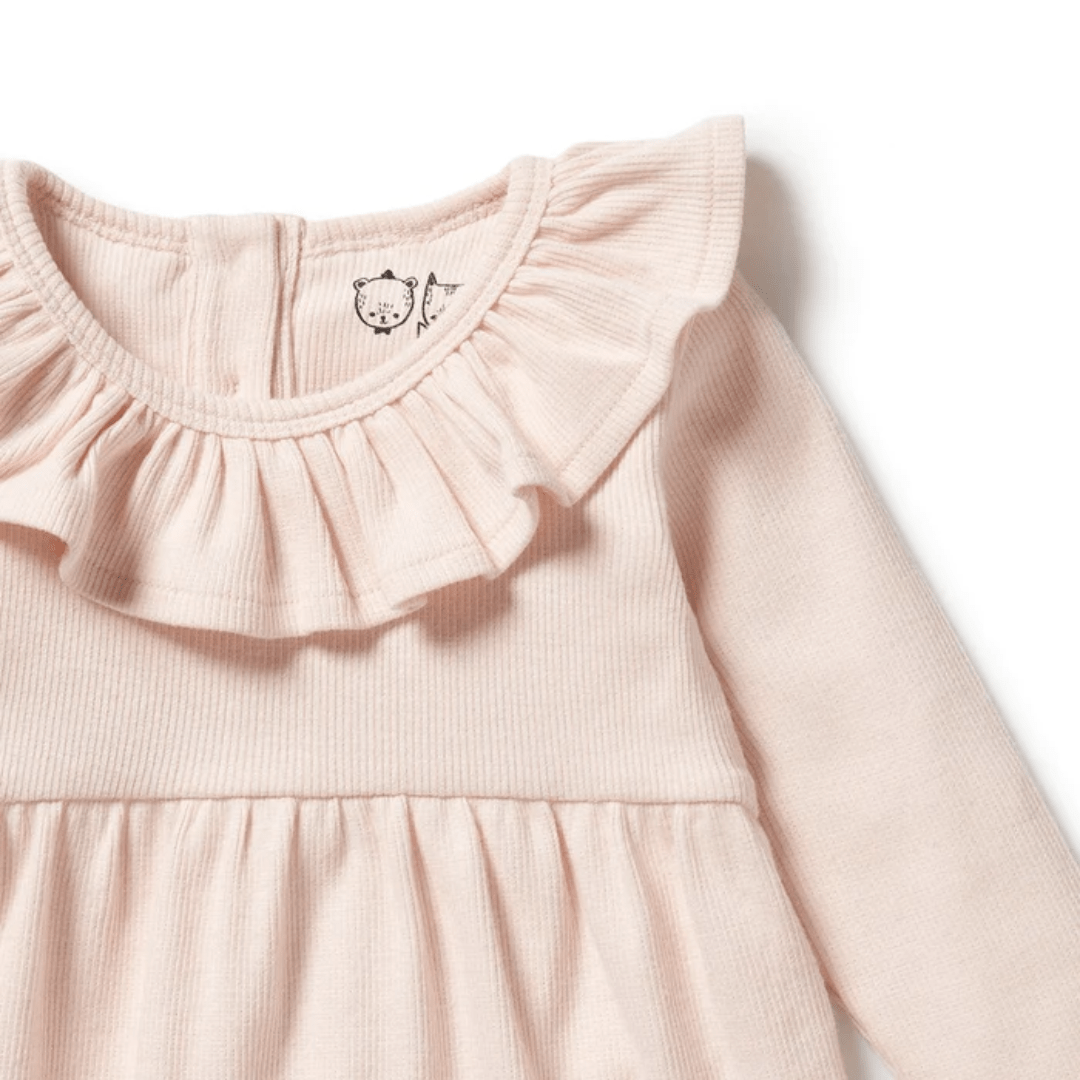 The Wilson & Frenchy Organic Rib Long Sleeved Ruffle Dress in a charming pink color is designed for babies aged 6–12 months and 18-24 months. This delightful dress features a ruffled collar, ribbed texture, and a small bear design near the neckline, showcasing the meticulous craftsmanship of Wilson & Frenchy.