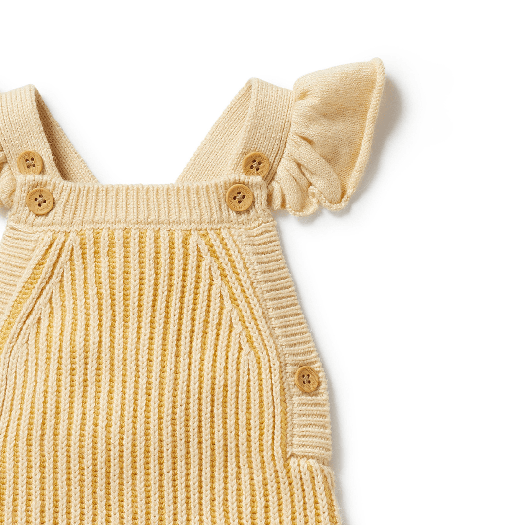 A close-up of Wilson & Frenchy's Knitted Ruffle Overalls, part of the LUCKY LASTS - DIJON ONLY collection, showcasing button details on the straps and sides, complete with ruffled shoulder accents.