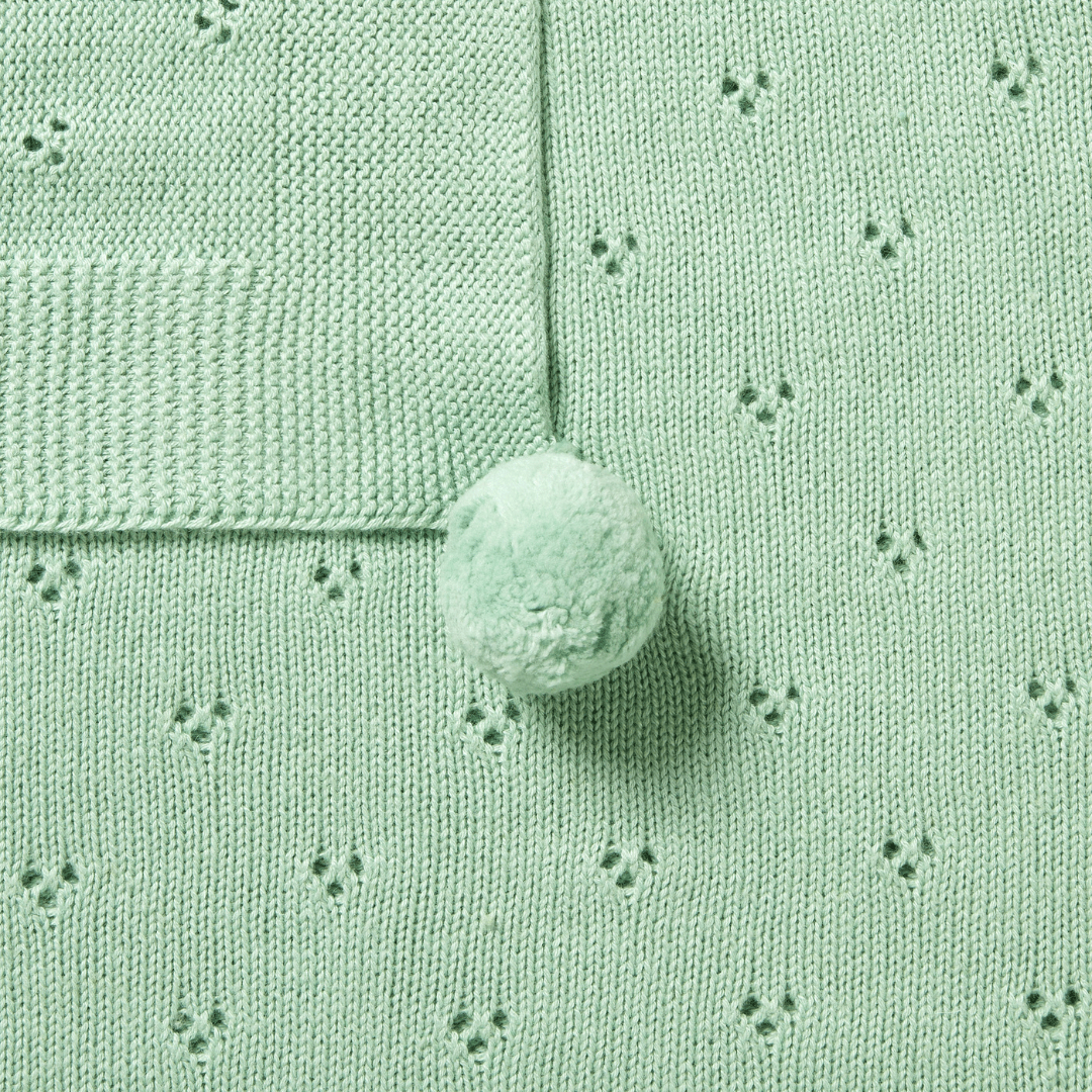 A close-up of a mint green pom adds the perfect finishing touch to the Wilson & Frenchy Knitted Pointelle Baby Blanket. This charming detail makes it an ideal baby shower gift, sure to be treasured for years.