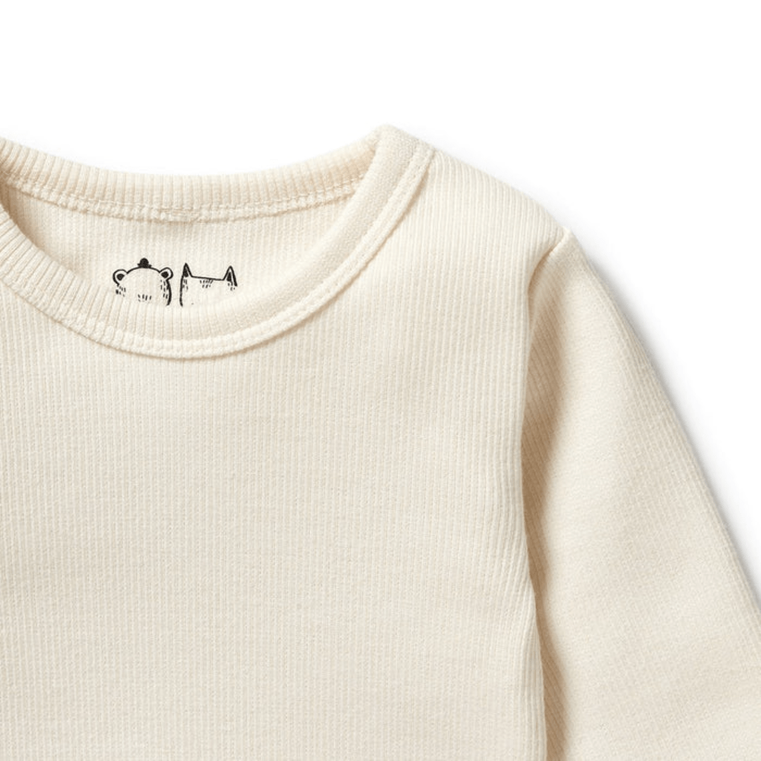 Close-up of the top half of a Wilson & Frenchy Organic Rib Long Sleeved Top—a cream-colored, ribbed, long-sleeve baby t-shirt crafted from organic cotton. Features a small bear illustration on the inside collar. Available in sizes 6-12 months and 12-18 months only.