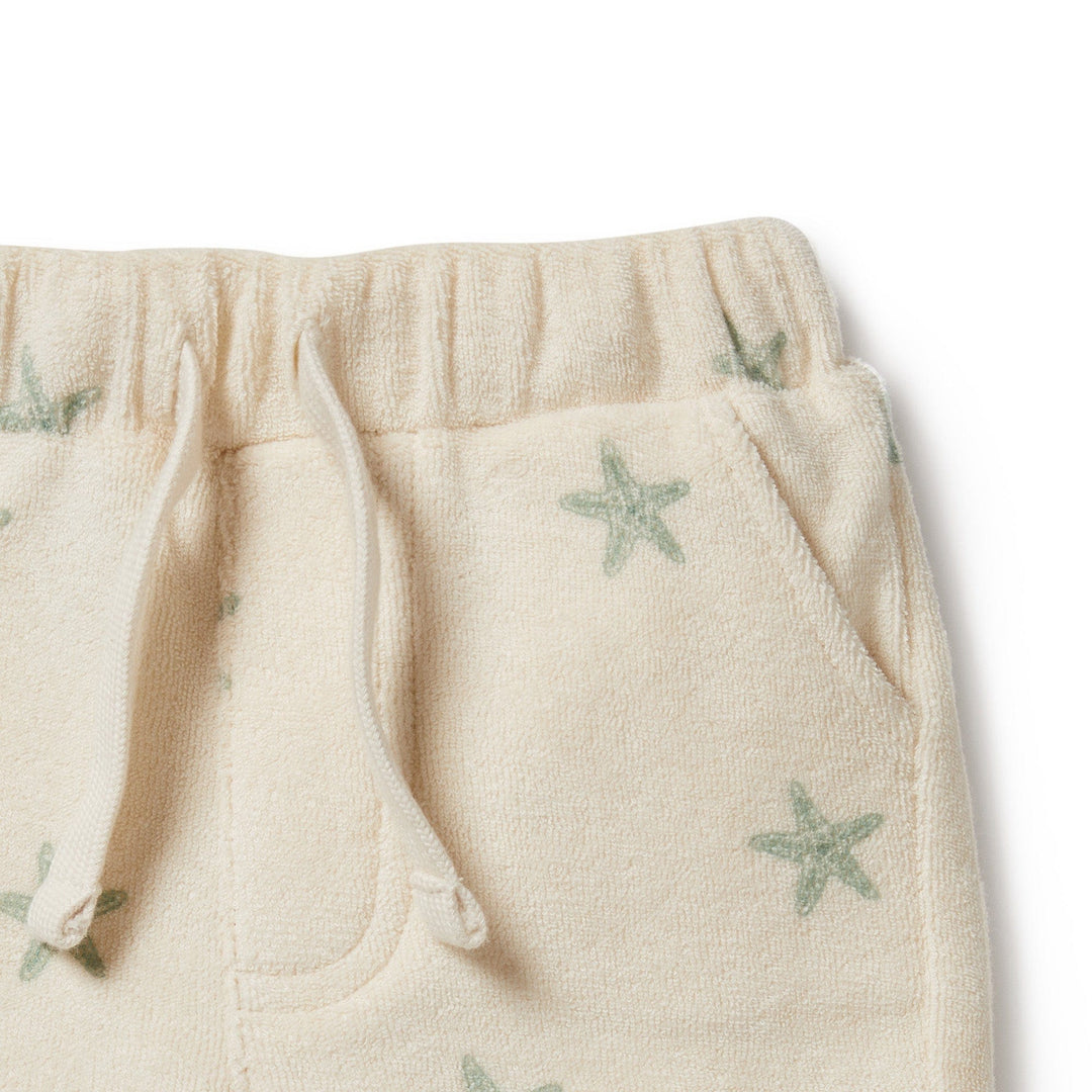 Close-up of the Wilson & Frenchy Organic Terry Shorts in a cream color with a drawstring and a green star pattern. Made from GOTS-certified organic cotton, these summer staples feature convenient pockets for added functionality. Suitable for ages 0-3 months.