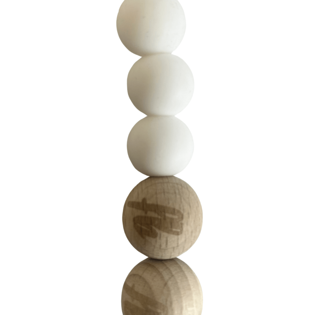 Four white spheres, resembling beechwood beads from the Funny Bunny Kids Silicone & Beechwood Dummy Clip, stacked on top of a wooden sphere with text on it, all elegantly reflected on a shiny surface.