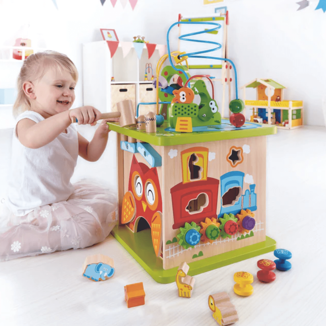 A child sets off on a safari adventure in the playroom with the Hape Wildlife Safari Adventure Centre - LUCKY LAST, a vibrant wooden activity cube featuring durable wood, gears, shapes, and a ball track designed to enhance cognitive development.