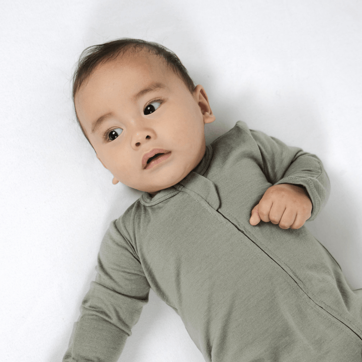 Little-Baby-Lying-Down-Wearing-Babu-Footless-Merino-Growsuit-Babu-Sage-Naked-Baby-Eco-Boutique