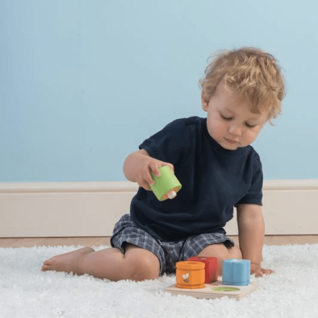 A young boy playing with a Le Toy Van Petilou Sensory Tray Set on the floor.