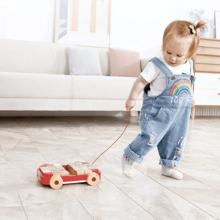 Little-Girl-Pulling-Along-Hape-Pull-Along-Cart-With-Stacking-Blocks-Naked-Baby-Eco-Boutique