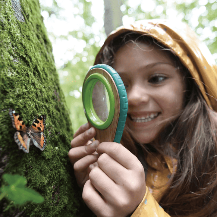 Little-Girl-Using-Magnifiying-Glass-With-Butterfly-Hape-Nature-Detective-Set-Naked-Baby-Eco-Boutique