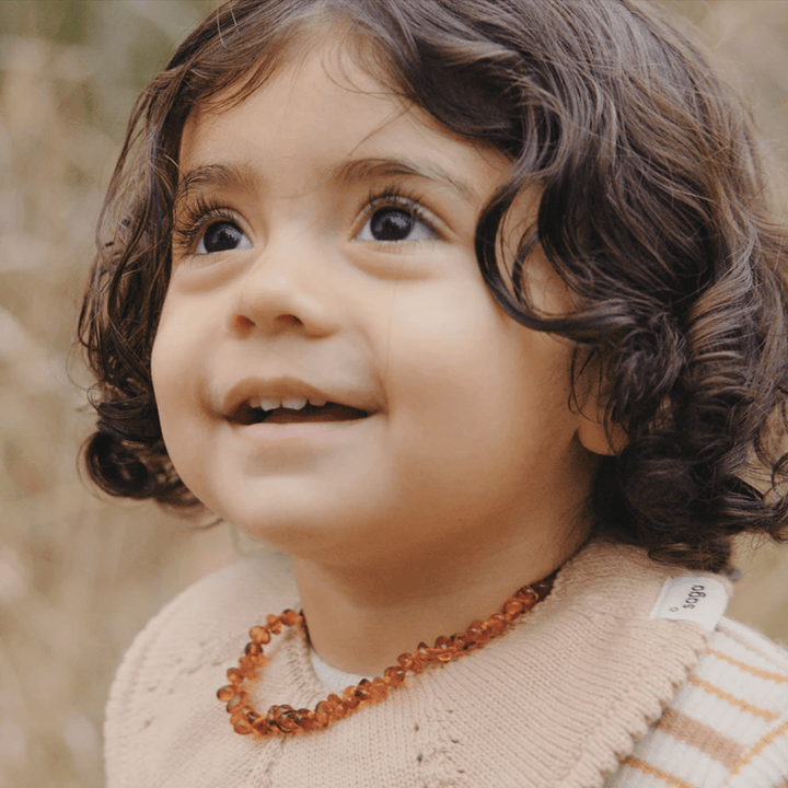 Little-Girl-Wearing-Saga-Copenhagen-Baltic-Amber-Teething-Necklace-Honey-Naked-Baby-Eco-Boutique