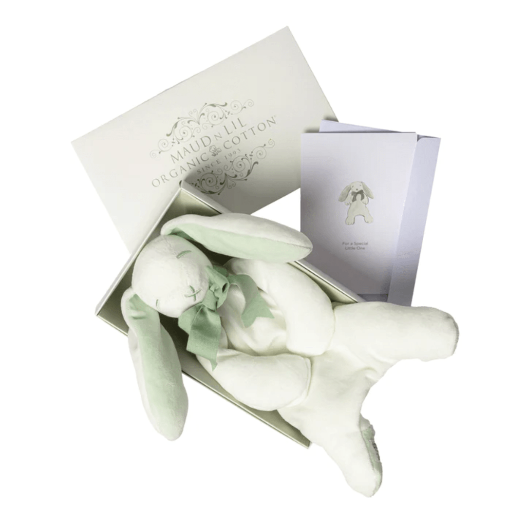 A Maud N Lil Organic Bunny Comforter - Gift Boxed with green ears and a bow is placed inside an open white box. A folded card with an image of the bunny is beside the box. "Maud N Lil" is written on the box lid, making it a charming organic cotton toy perfect as a baby gift.