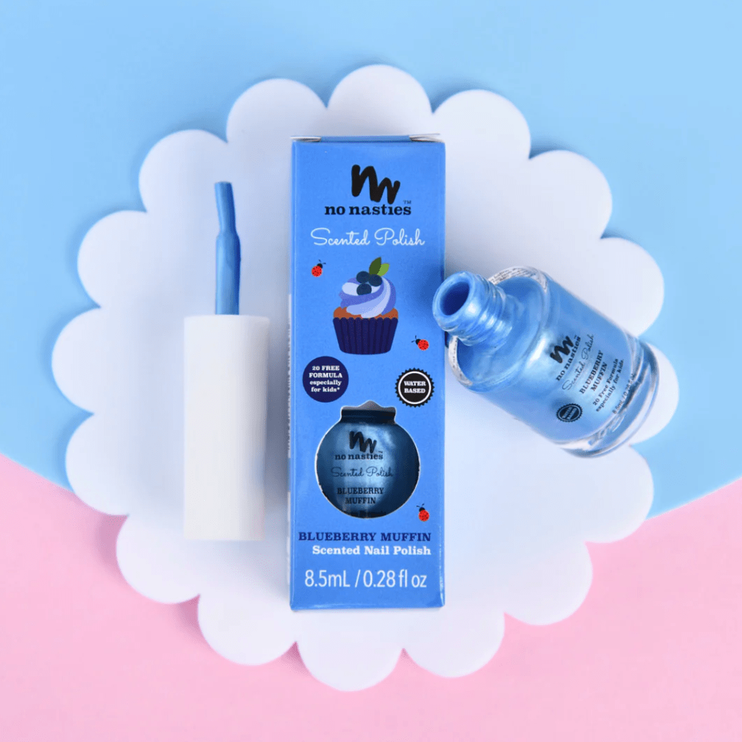 No Nasties 20 FREE Kids Scented Nail Polish, featuring a blueberry muffin fragrance, presented in a blue bottle and accompanied by its matching blue box, set against a charming scalloped white and pink backdrop.