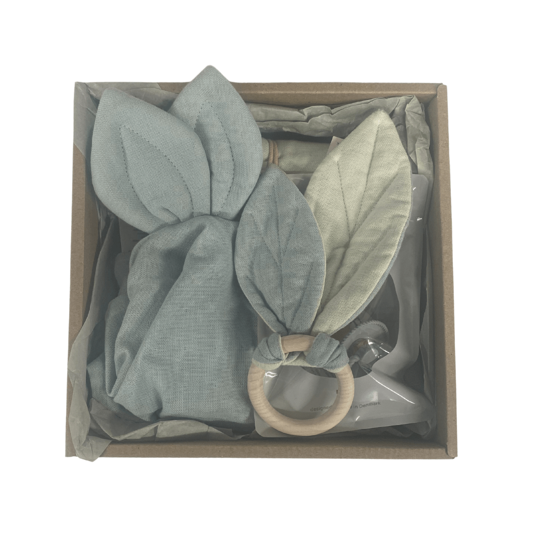 The Saga Copenhagen Gift Box - Elina features a soft toy with fabric leaves and a wooden teether ring, each in calming green hues. Made from organic cotton, this charming set is presented in eco-friendly packaging, ideal for those who prioritize sustainability.