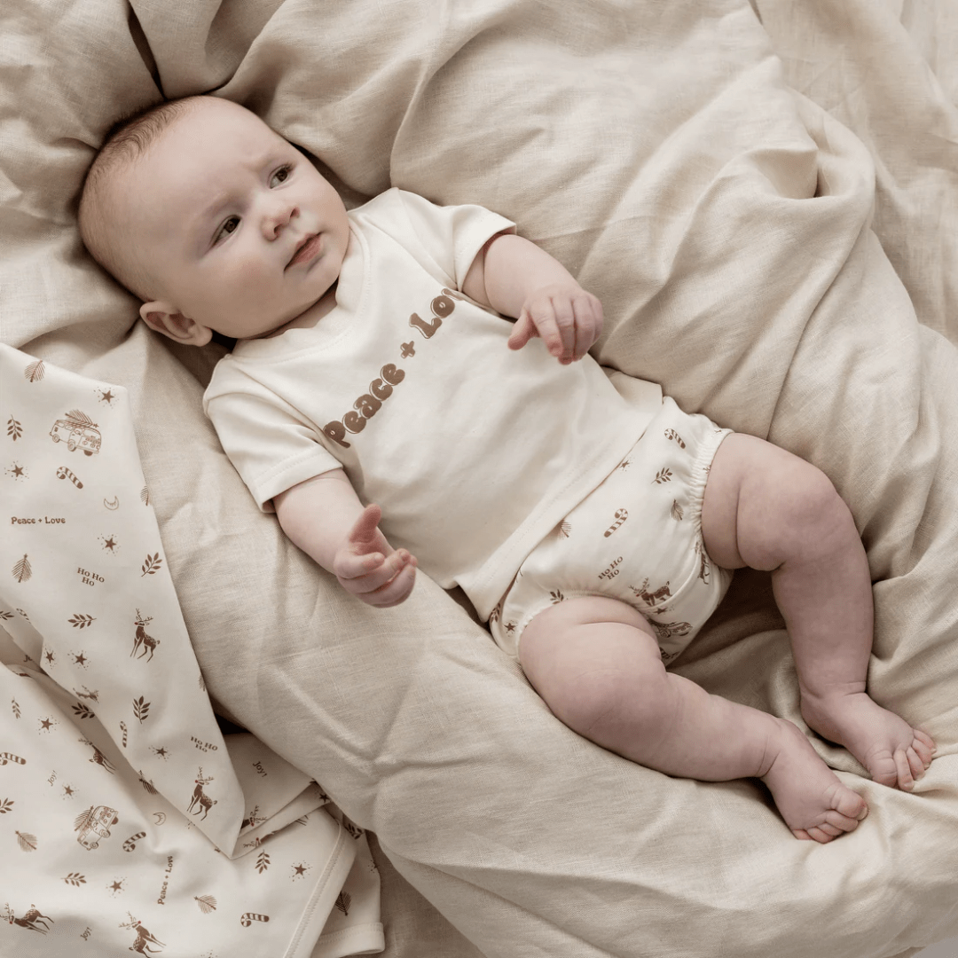 Styled-Image-Of-Aster-And-Oak-Organic-Happy-Holidays-Baby-Swaddle-Wrap-Naked-Baby-Eco-Boutique