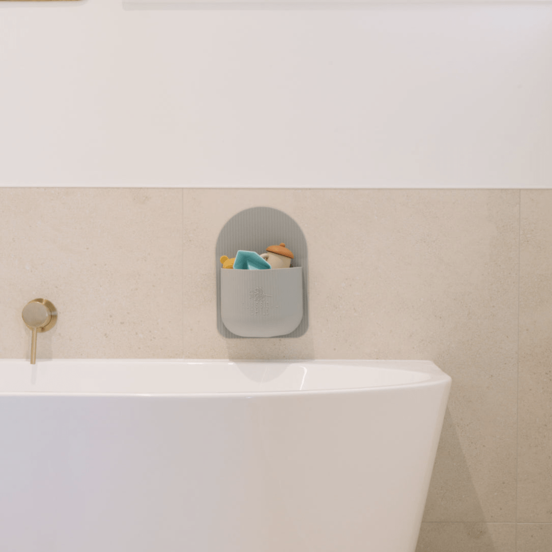 A minimalist bathroom features a white tub complemented by the Classical Child Silicone Bath Toy Caddy - LUCKY LASTS, a BPA-free organiser from Classical Child that holds colorful toys.