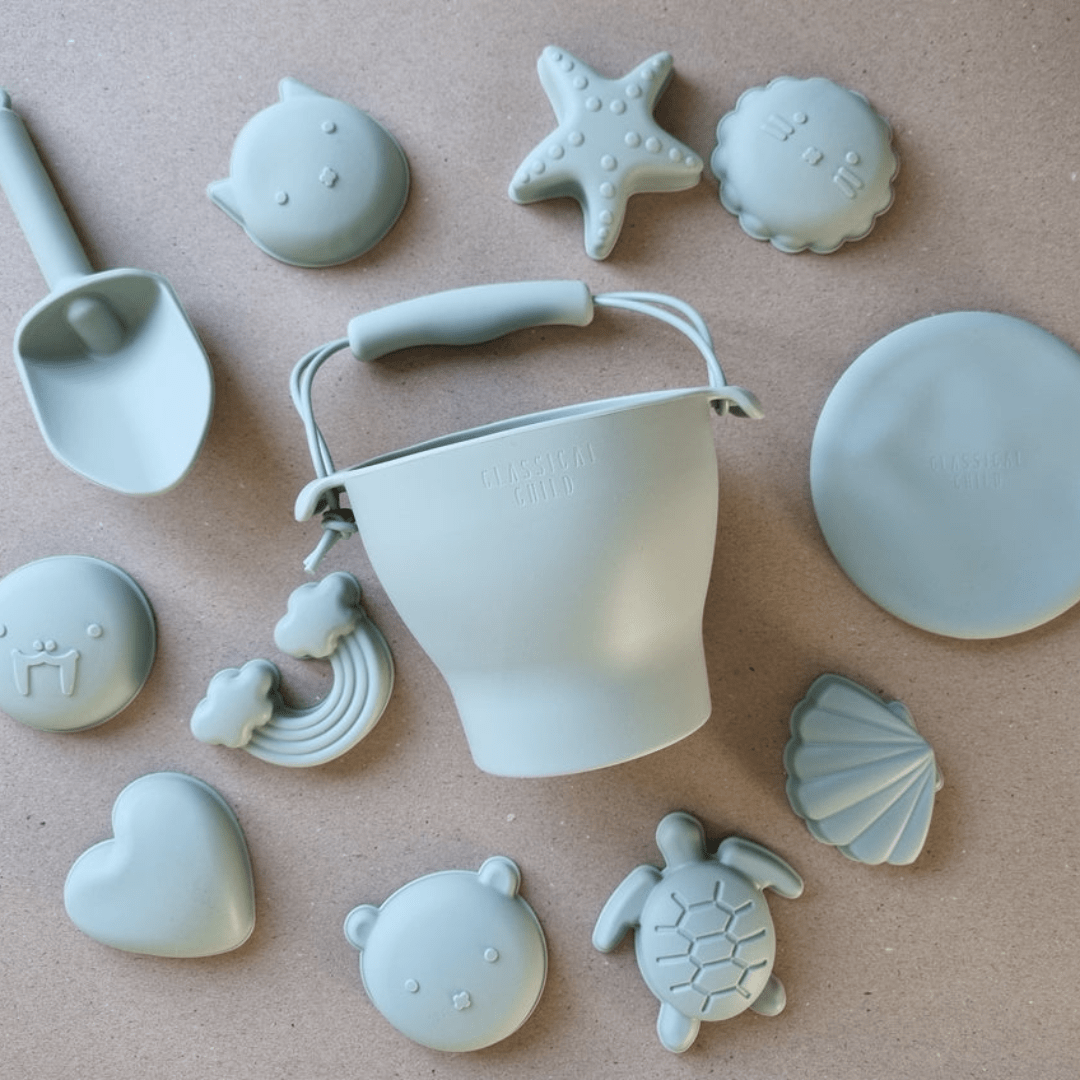 A set of Classical Child Silicone Beach Bucket Set With Frisbee including beach molds and shells.