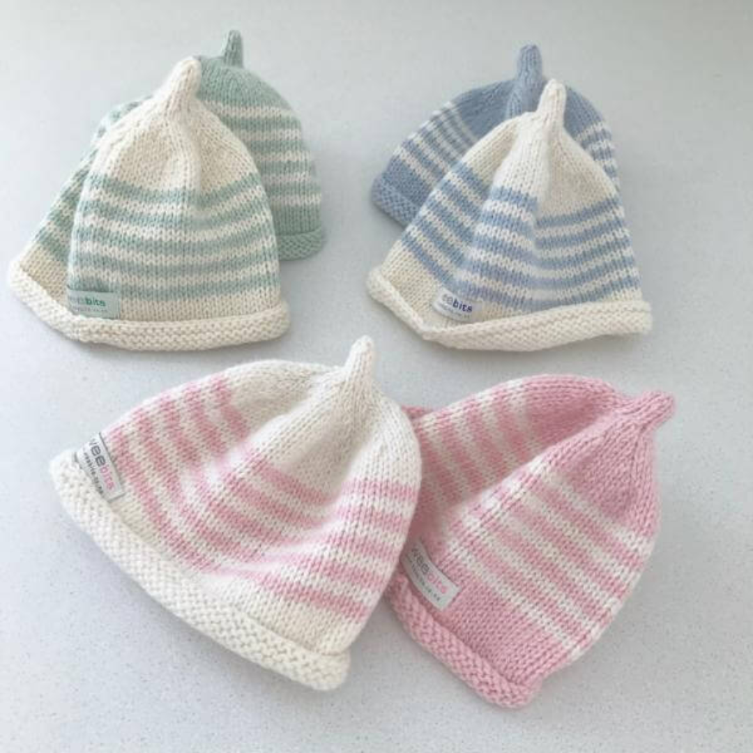 Five Weebits Merino Knit Baby Hats in pink with white stripes are displayed on a white surface.