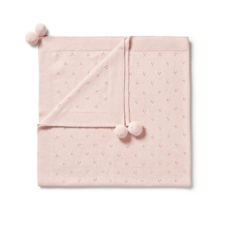 The Wilson & Frenchy Knitted Pointelle Baby Blanket in mint green, adorned with delicate dotted patterns and three pom-poms at the corners, makes a perfect baby shower gift.