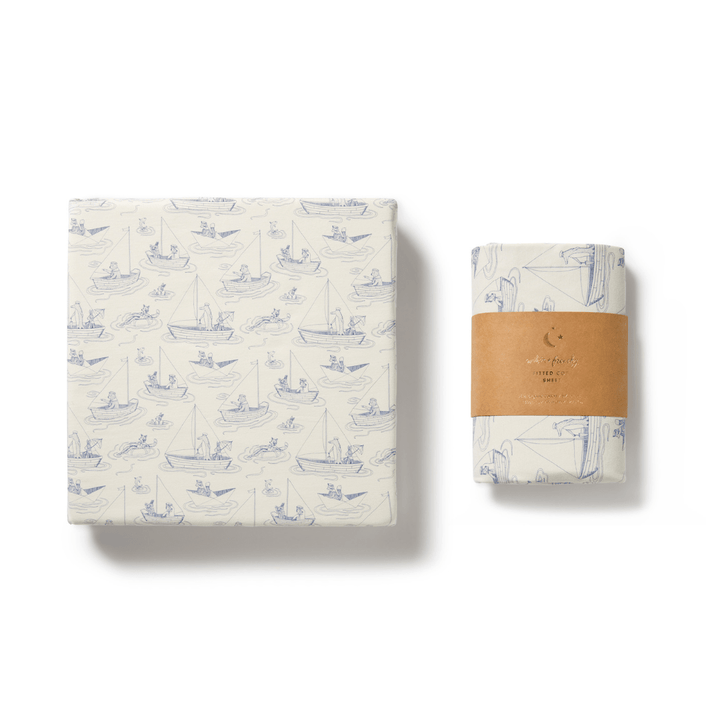 A Wilson & Frenchy Organic Cotton Cot Sheet - the perfect baby shower gift, wrapped in matching nautical-themed paper with a smaller rectangular package.