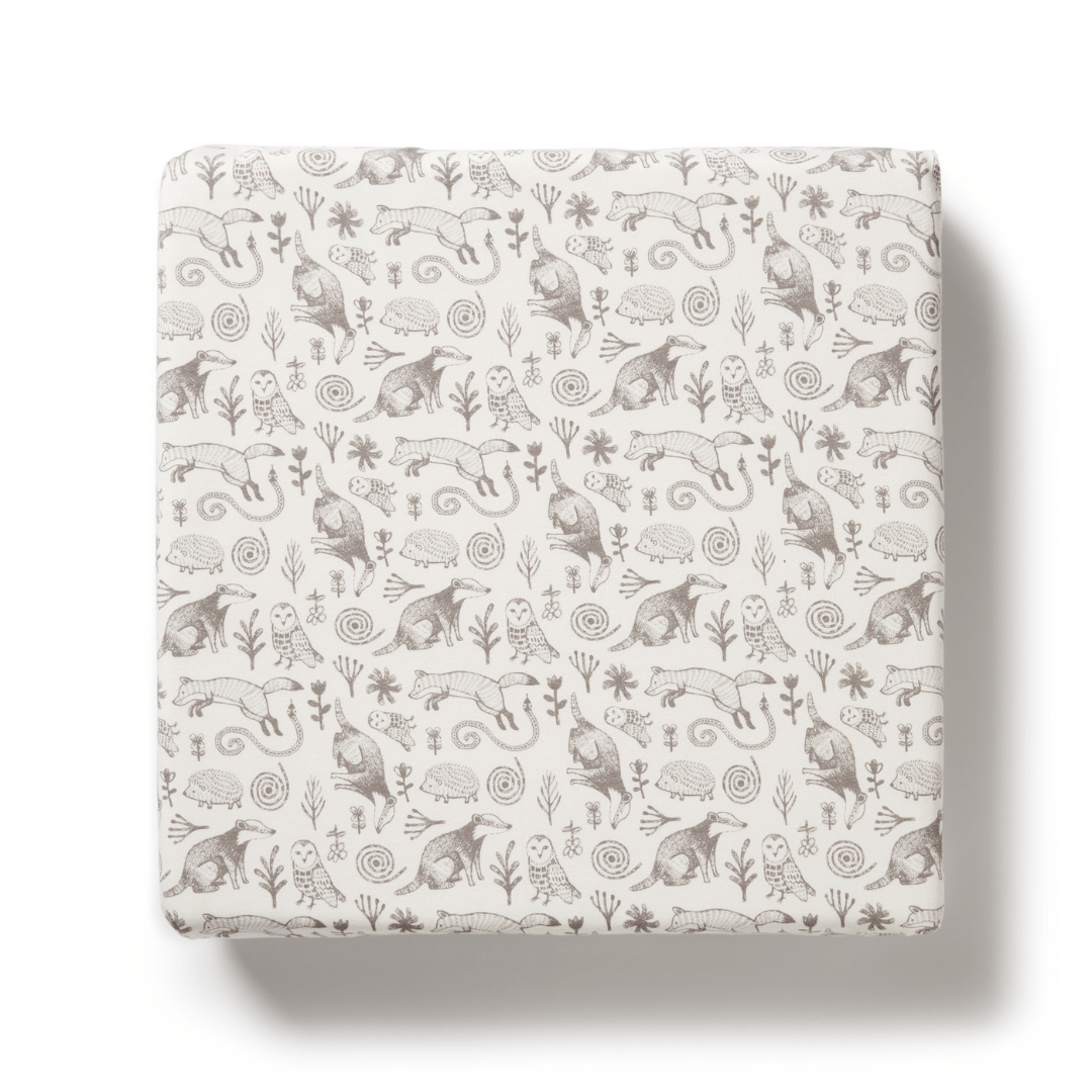 Introducing the Wilson & Frenchy Organic Cotton Cot Sheet - LUCKY LAST - TRIBAL WOODS ONLY: a beautiful cot sheet with a beige base adorned with intricate patterns of various animals and plants in monochromatic grey, making it an ideal accent piece or a perfect addition to a baby shower gift.