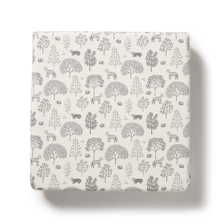 A charming Wilson & Frenchy Organic Cotton Cot Sheet - LUCKY LAST - TRIBAL WOODS ONLY in white, featuring a grey pattern of various animals, trees, and plants—ideal as a GOTS-certified Baby Shower Gift.