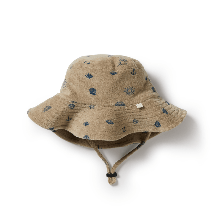 Introducing the Wilson & Frenchy Organic Terry Kids Sunhat, available in the SUNDIAL ONLY design. This beige sunhat is adorned with small blue nautical and sun-themed patterns, crafted from organic cotton for enhanced comfort, and includes a chin strap to ensure added sun protection.