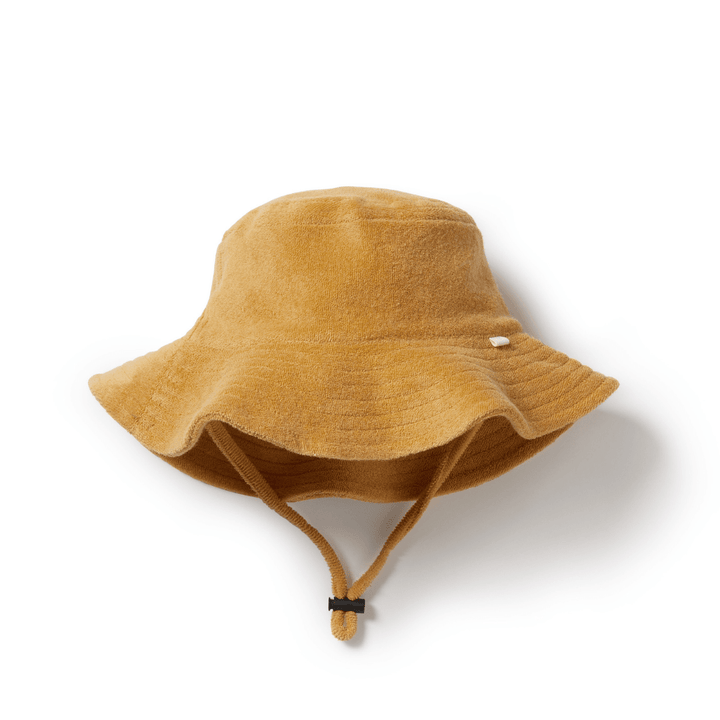 The Wilson & Frenchy Organic Terry Kids Sunhat in the Sundial color is a mustard yellow bucket hat made from organic cotton, complete with an adjustable chin strap for secure sun protection, showcased against a white background.