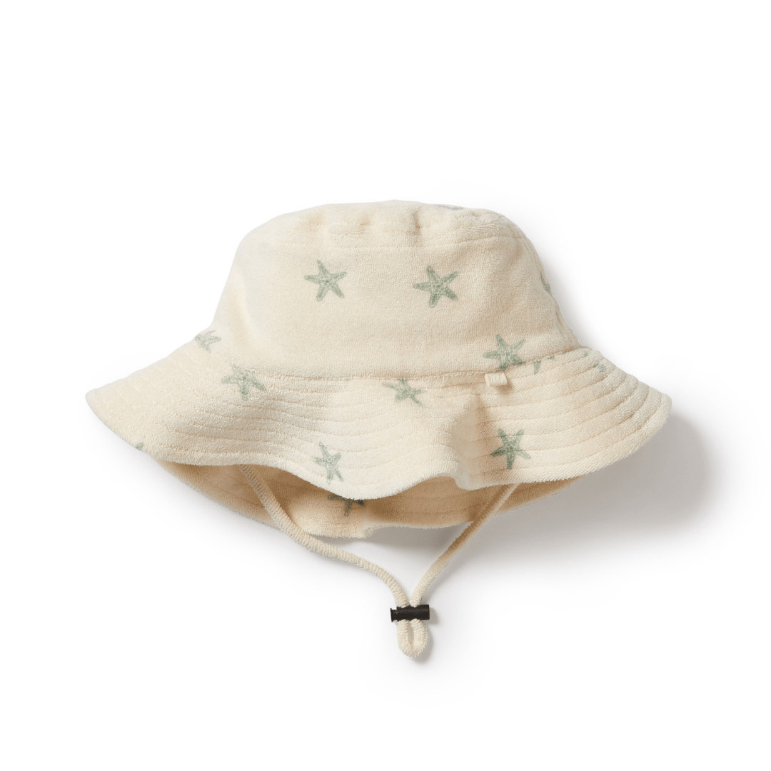 Introducing the Wilson & Frenchy Organic Terry Kids Sunhat in Sundial, a stylish kids' sunhat combining comfort and safety. This floppy-brimmed hat features a charming star pattern and an adjustable chin strap for optimal sun protection, making it perfect for sunny weather.