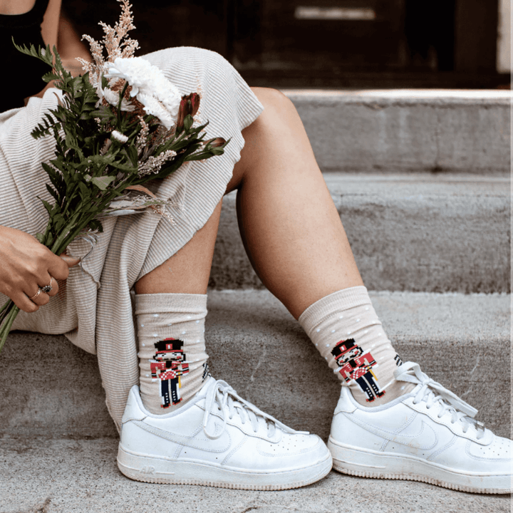 This Lamington product description showcases a woman donning a pair of white sneakers with Lamington Merino Wool Christmas Socks - Crew - Nutcracker - LUCKY LASTS - 8-12 YEARS ONLY, perfect for outfitting any ensemble.