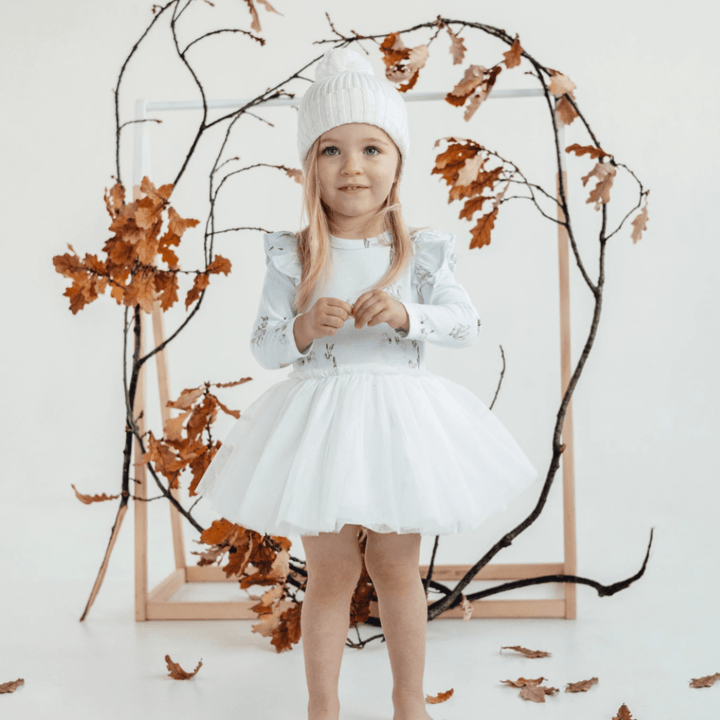 Adorable-Little-Girl-with-Clasped-Hands-Wearing-Aster-and-Oak-Organic-Cotton-Pom-Pom-Beanie-Snow-Naked-Baby-Eco-Boutique