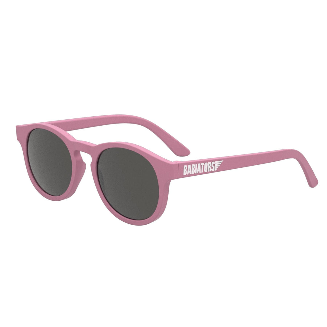 Pink round sunglasses with dark lenses, featuring flexible rubber frames and the brand name "Babiators" printed on the temple. Enjoy 100% UVA and UVB protection while rocking these stylish Babiators Keyhole Baby & Kids Sunglasses (Multiple Variants) by Babiators.