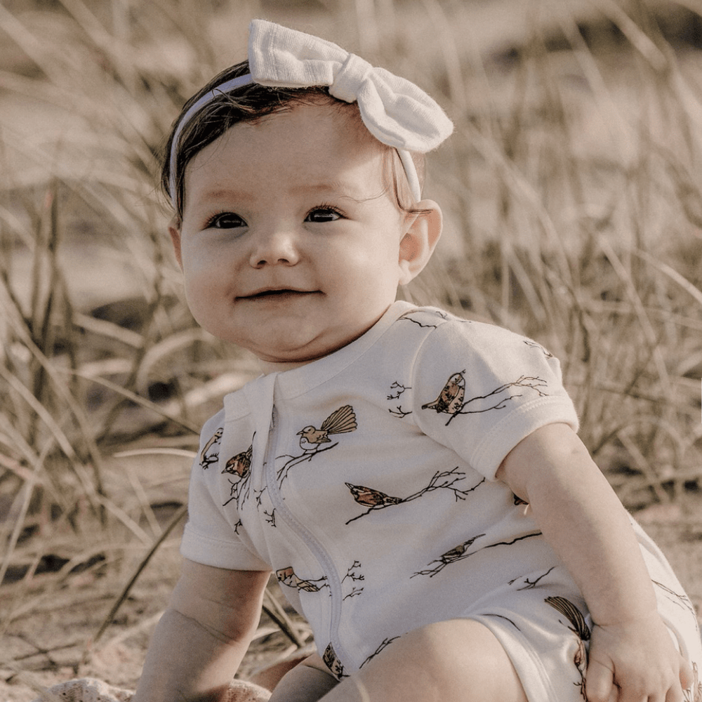 Baby-Girl-Sitting-Smilint-Wearing-Aster-and-Oak-Organic-Bird-Zip-Romper-Naked-Baby-Eco-Boutique