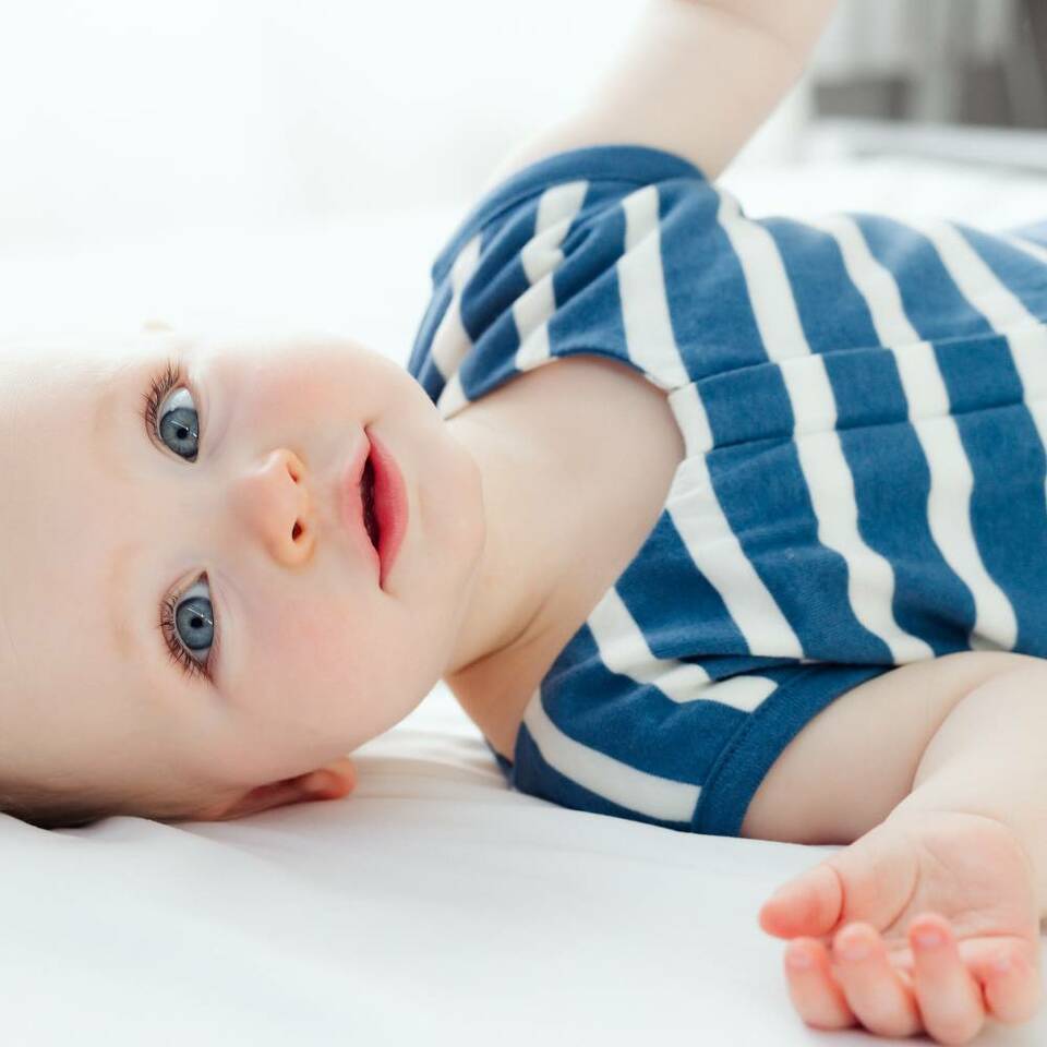 Close-up-of-Blue-Eyed-Baby-Wearing-Woolbabe-3-Seasons-Organic-Cotton-Merino-Sleeping-Bag-River-Stripe-Naked-Baby-Eco-Boutique