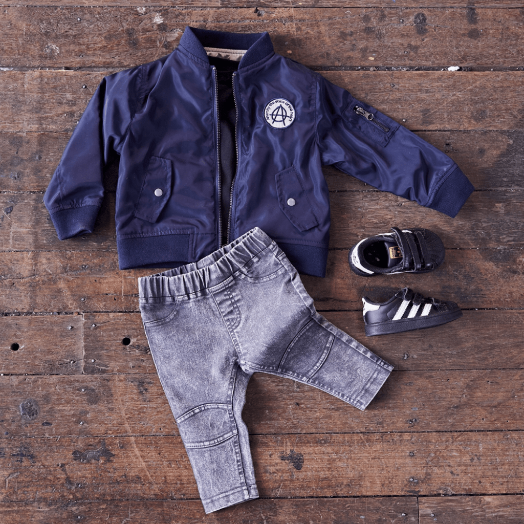 An Anarkid baby boy's bomber jacket, jeans and shoes on a wooden floor.