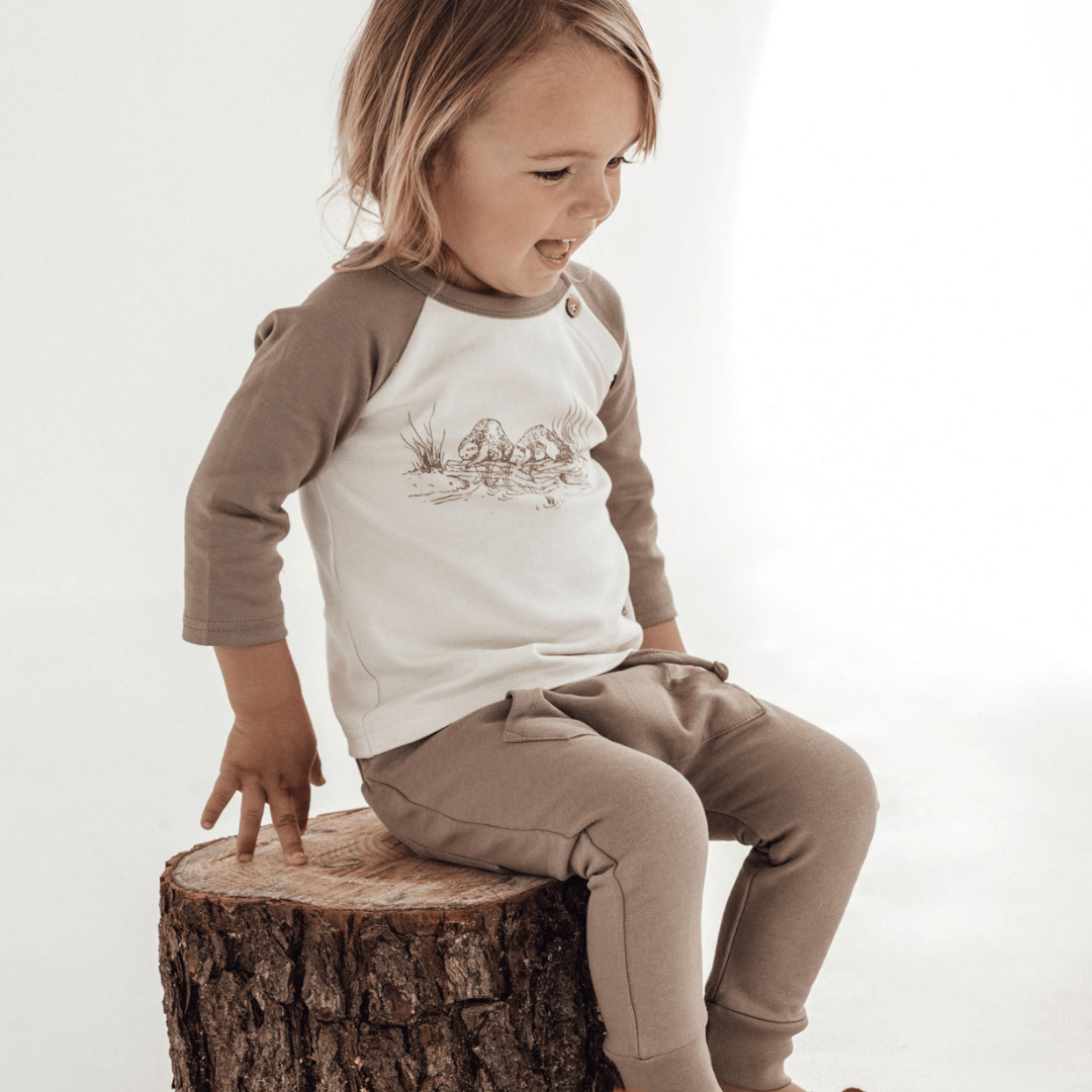 Little-Boy-Sitting-on-Stump-Wearing-Aster-and-Oak-Organic-Beaver-Raglan-Tee-Naked-Baby-Eco-Boutique