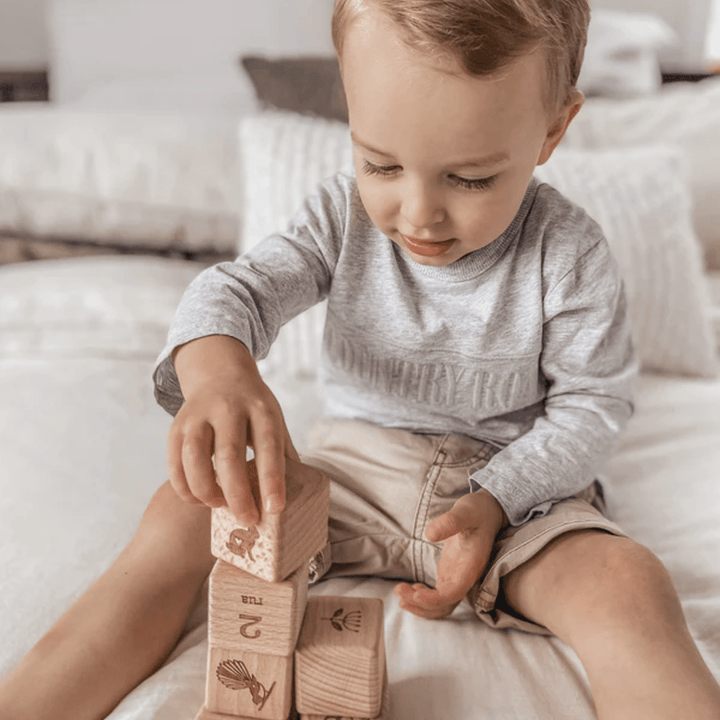 Little-Boy-Stacking-Over-The-Dandelions-Tahi-Rua-Toru-Wooden-Block-Set-Naked-Baby-Eco-Boutique