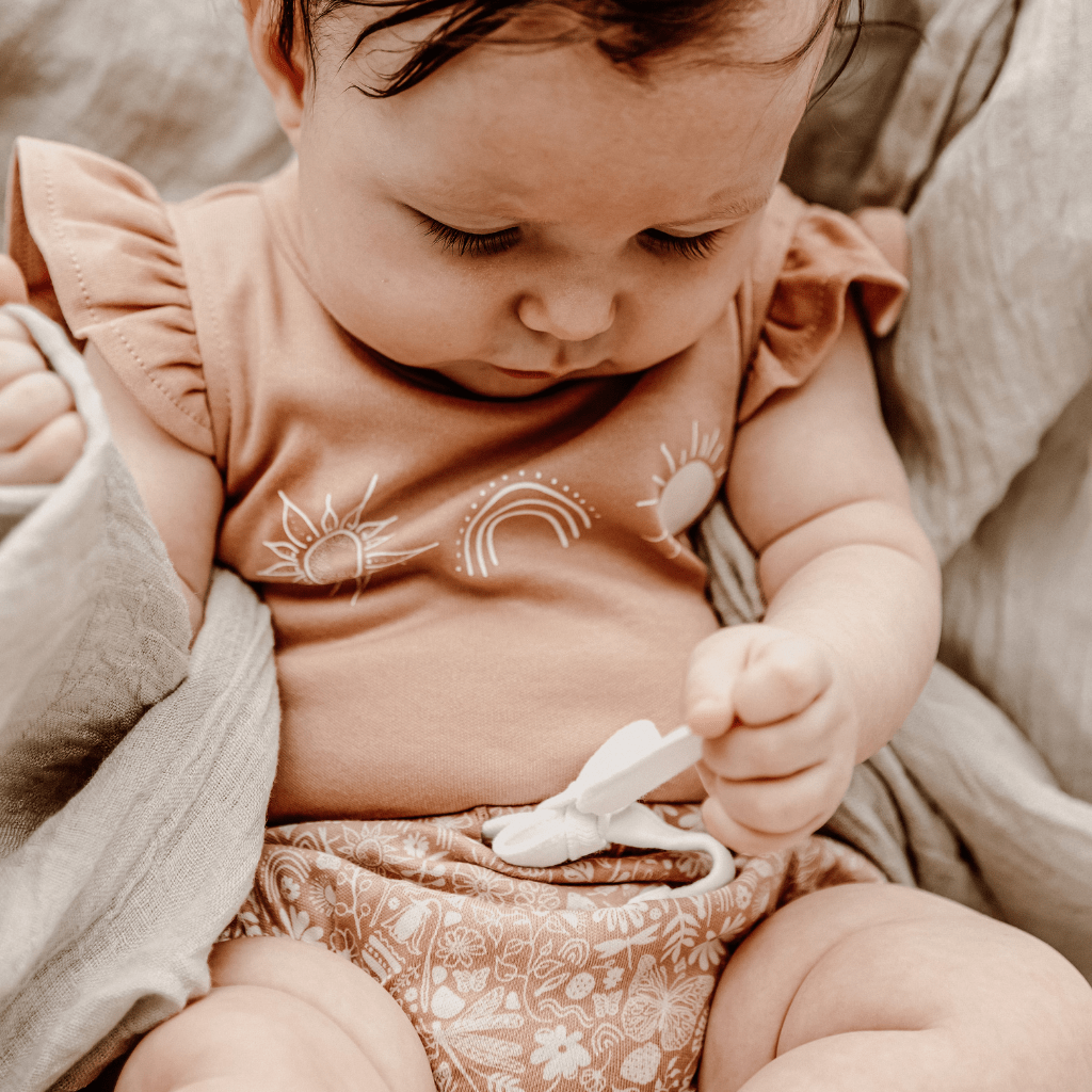 Little-Girl-Playing-with-Tie-on-Aster-and-Oak-Organic-Ditzy-Floral-Bloomers-Naked-Baby-Eco-Boutique